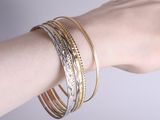 a woman ' s arm with three different bracelets on it