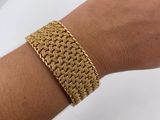 a close up of a person ' s hand wearing a gold bracelet