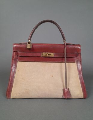 a red and beige bag with a handle on a gray surface