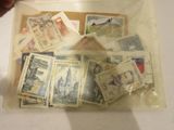 un sachet de timbres posé sur une table, à côté d'une personne tenant une paire de ciseaux