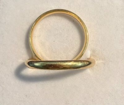 a gold ring with a curved band on a white surface