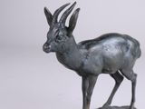 an image of a statue of a deer standing on top of a wooden base