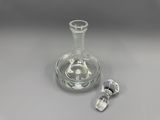 une bouteille en verre posée sur une table, avec un bouchon à côté