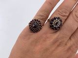 woman ' s hand with red manicured nails and two rings on it
