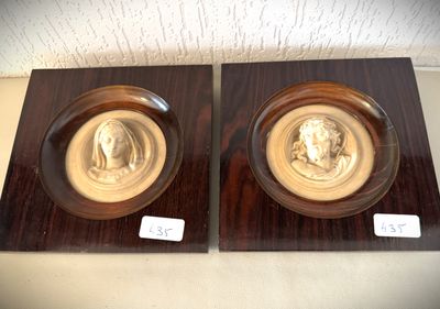 pair of two wooden plaques with two heads of a man and a woman on them