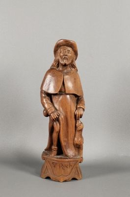 une vieille statue en bois représentant un homme avec un chapeau et une canne