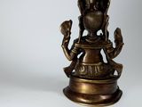 brass figurine of a person holding a bird on a pedestal