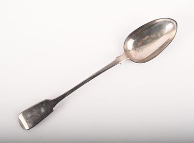 une cuillère en argent à long manche posée sur une surface blanche