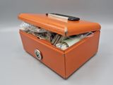 une petite boîte orange contenant de l'argent