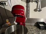 a red mixer sitting on a kitchen counter next to a metal bowl
