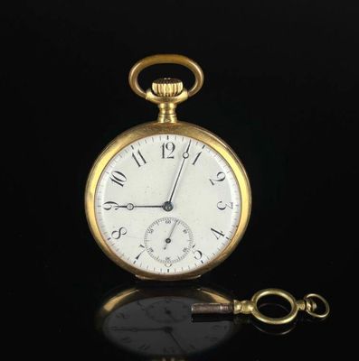 an antique pocket watch on a black surface with a key