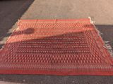 un tapis posé sur le trottoir devant une voiture garée sur le bord de la route