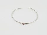 un gros plan sur un bracelet rigide en argent orné d'une pierre rouge