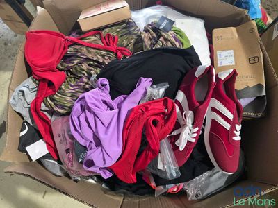 une boîte en carton remplie de vêtements et de chaussures posée par terre