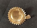 a close up of a gold plated pendant on a black cloth