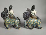 two figurines of a woman sitting on a horse with a basket on its back