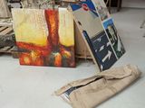 un tas d'œuvres d'art par terre, à côté d'une pile de livres