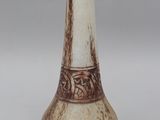 a white and brown vase with a brown design on it