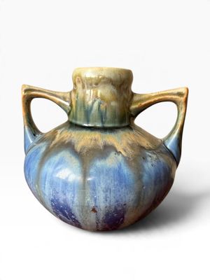 a blue and brown vase with handles on a white background