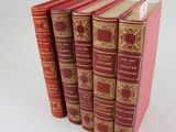quatre livres rouges empilés les uns sur les autres sur une surface blanche