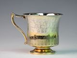 a silver cup with a handle sitting on a table