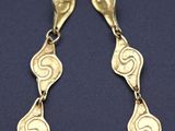 a pair of gold earrings with swirl designs on them
