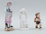 three porcelain figurines of children and a dog on a white surface