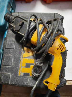 a yellow corded drill and a black corded hammer on a table