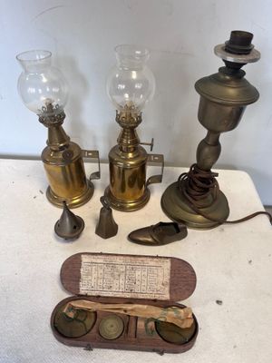 trois lampes anciennes en laiton et un papier posés sur une table