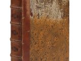 un vieux livre à la couverture brune posé sur une surface blanche