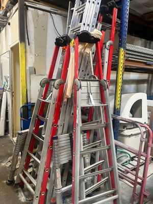 de nombreuses échelles empilées les unes sur les autres dans un garage