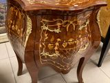 a small chest of drawers in a room with a painting on the wall behind it