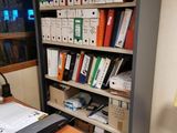 a desk with a laptop and a printer in front of a bookshelf
