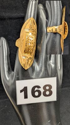 une bague en or ornée d'un poisson, au doigt d'une main