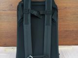 a black backpack with a tag on it on a bed