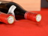 two bottles of wine sitting on a red cloth