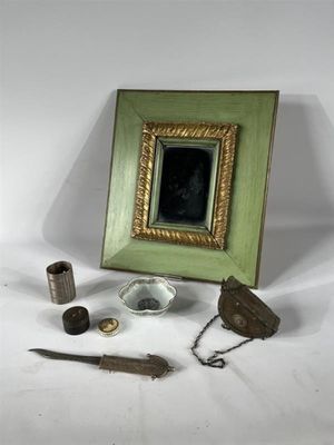 une photo représentant un cadre, une image, un couteau et d'autres objets posés sur une surface blanche