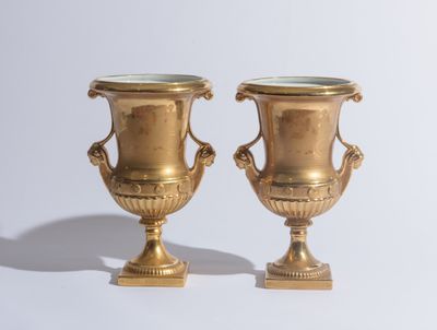 deux vases en or posés l'un à côté de l'autre sur une table