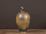 a vase with a bird on top of it sitting on a table