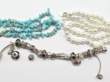 deux colliers ornés de perles et de breloques sur un fond blanc