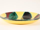 yellow, green, and red bowl with black and white design