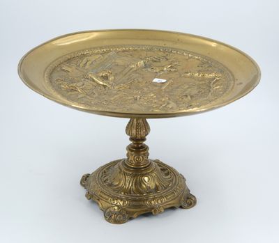 an antique brass plate on a pedestal on a white background