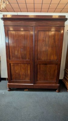 a wooden armoire in a room with a chandelier