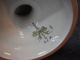 a close up of a white vase with a green flower on it