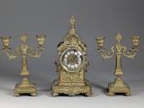 three candles and a clock sitting on a table