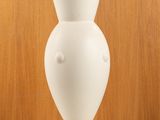 a white vase sitting on a table with a wooden wall in the background