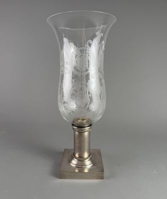un vase en verre posé sur une table, avec un socle en métal