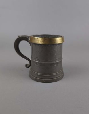 une vieille tasse ébréchée, bordée d'or, repose sur une surface grise