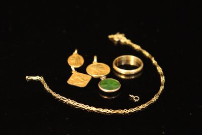 some gold and green jewelry sitting on a black surface