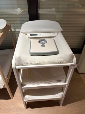 a small table with a scale on it next to a bed